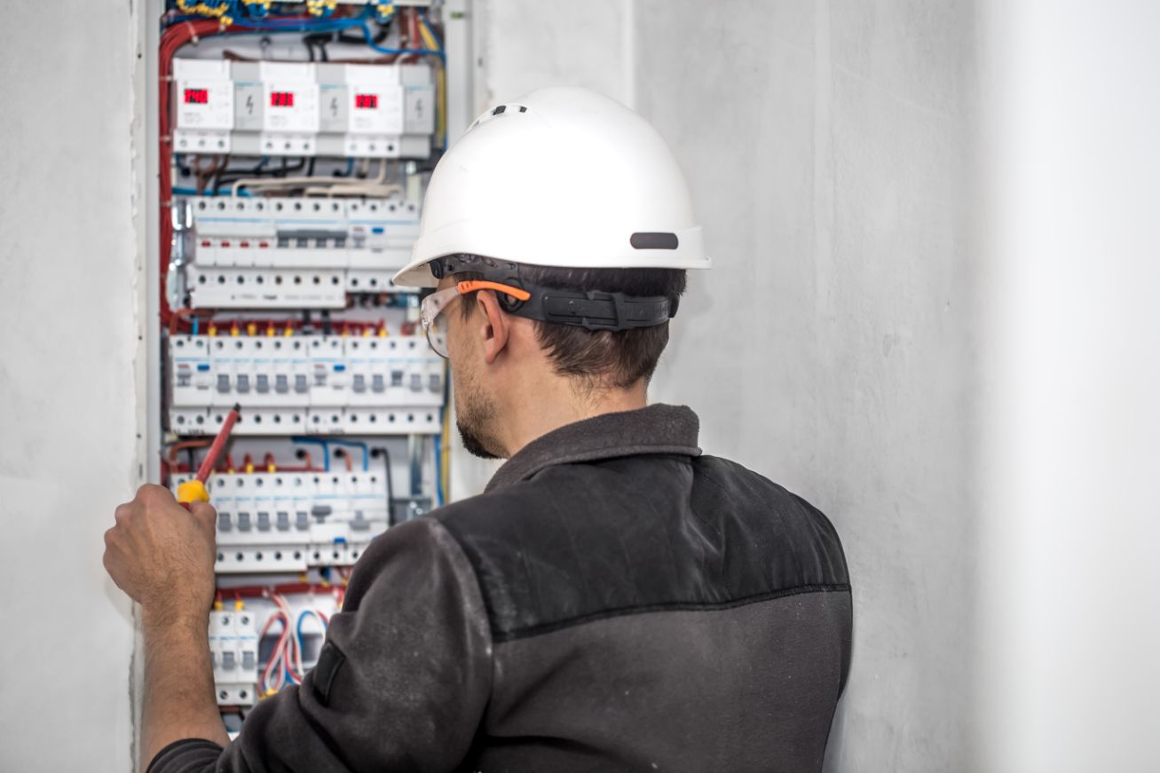 A close-up of a man with a safety hat holding electrical equipment taken while providing electrical service in NSW, Sydney, Australia.